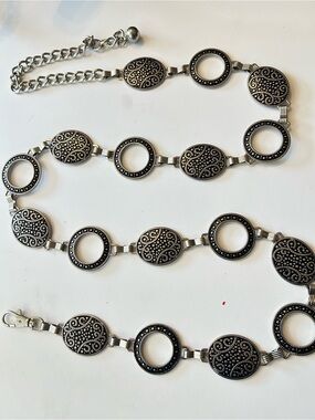 Silver-tone chain belt features textured medallion links and a hook closure L/XL